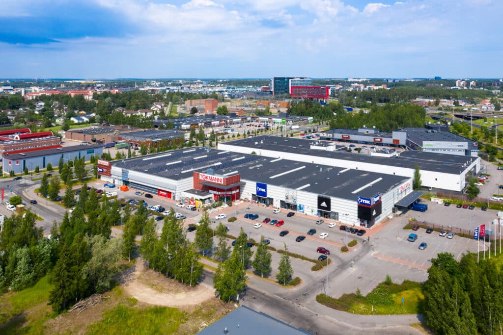 Toimitilakiinteistö Vantaan Nilsaksentie 2 ilmakuvassa. Rakennuksen katolla on aurinkopaneleita, pihalla runsaasti pysäköintitilaa.